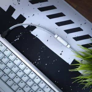 A close-up of a white mechanical keyboard, a braided cable with a YC8 connector, and green artificial grass on a black-and-white patterned desk mat.