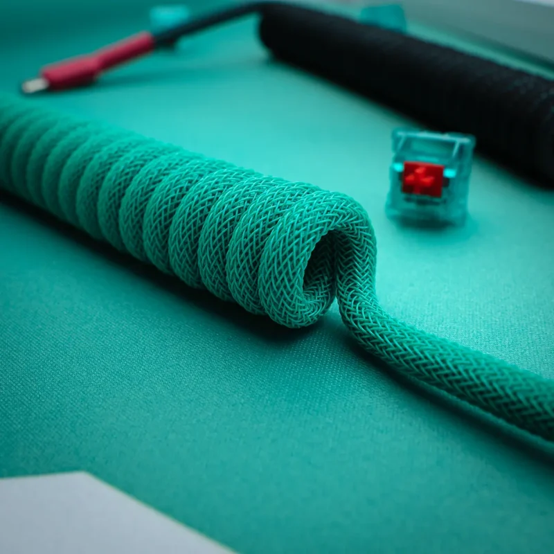 Coiled custom keyboard cable in vibrant teal, featuring sleek braiding, a straight section, and detachable connectors. Ideal for enhancing your setup.