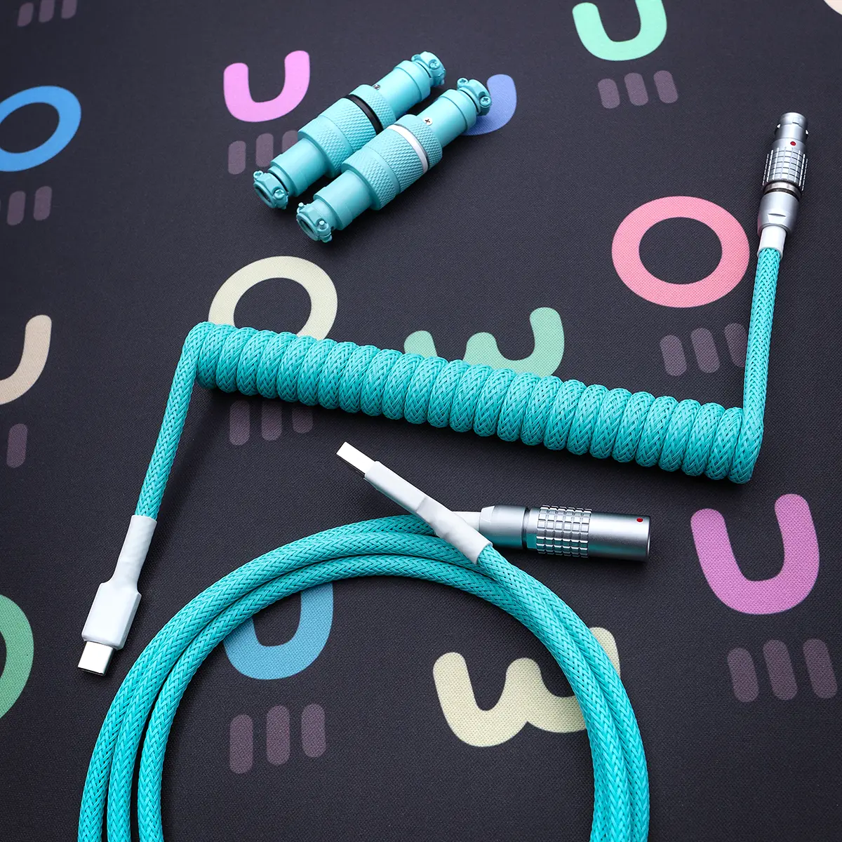 A vibrant turquoise coiled keyboard cable featuring detachable USB-C and aviator connectors, wrapped in a durable, textured braid for stylish functionality.
