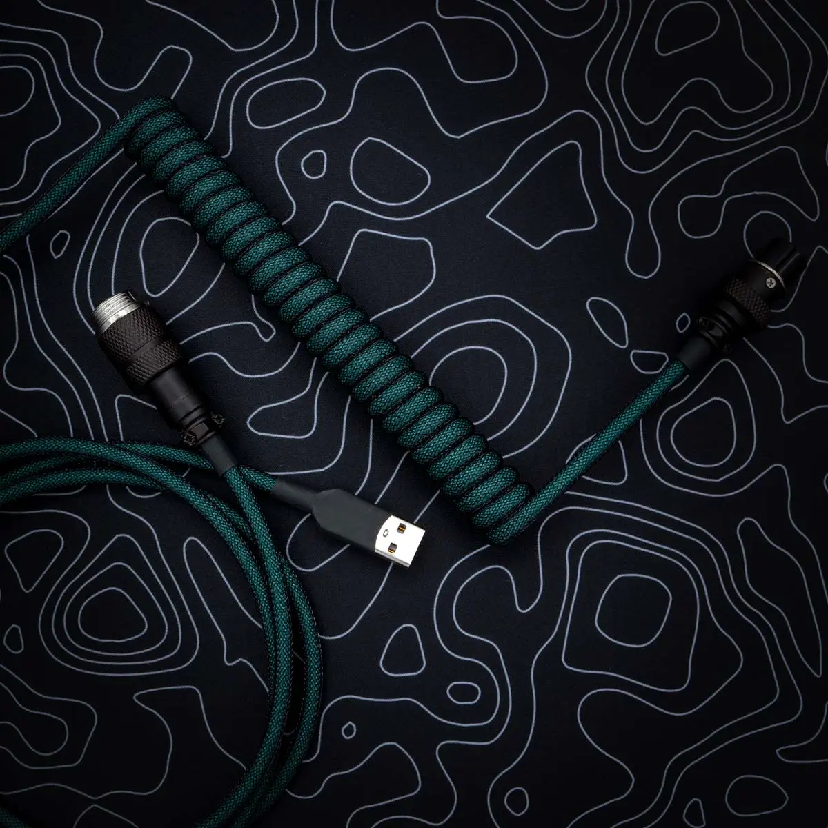 Green coiled keyboard cable features a USB-C connector and a detachable aviator plug. The paracord texture enhances durability and style.