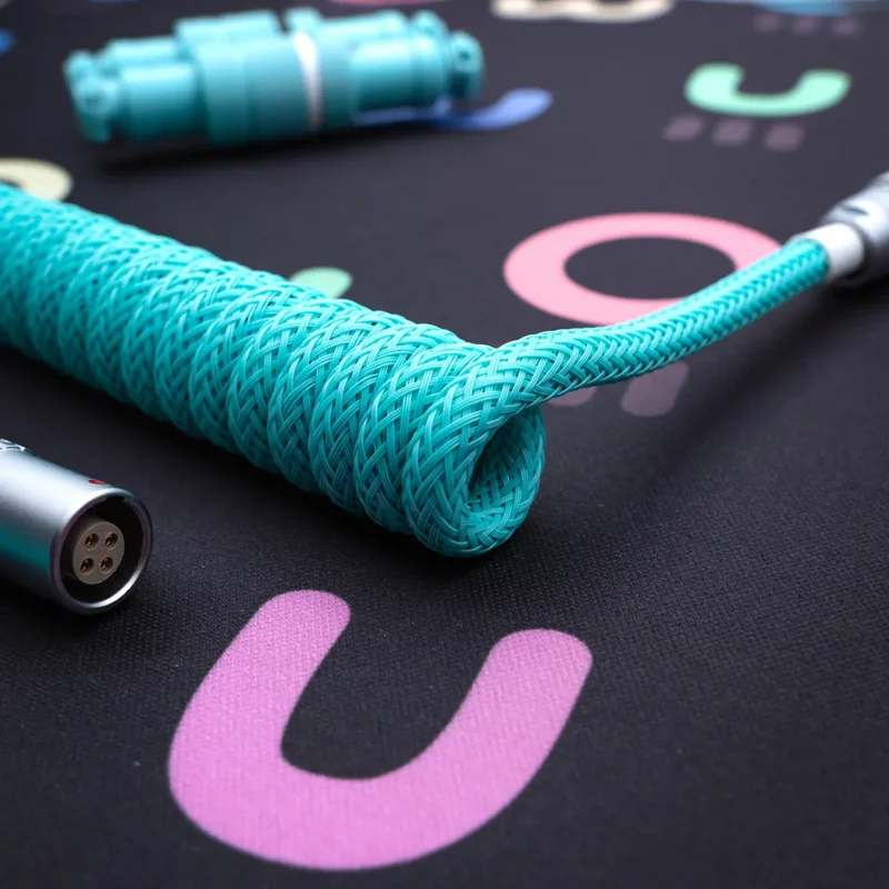 Coiled turquoise keyboard cable with sleek braided finish, featuring detachable connectors and high-quality metal housing for durability and style.