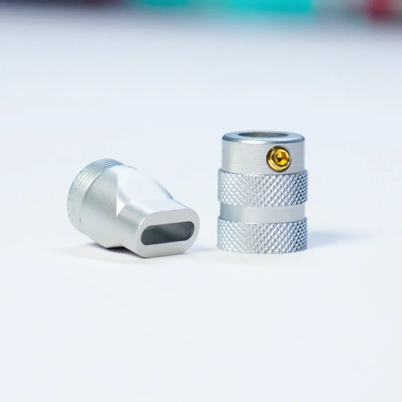 Two silver metal fittings with knurled grip, one is upright with a visible screw, the other lies on its side showing a rectangular opening. Precision-made for USB Type C - Housing CNC applications.