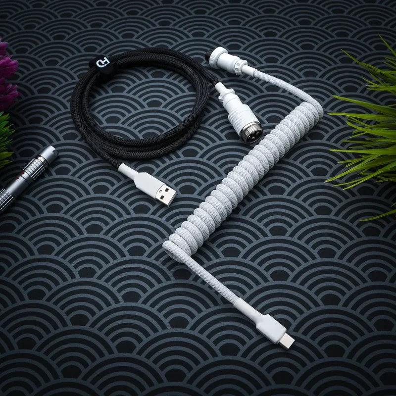 Curled white paracord cable with USB-C and aviator connectors, plus a black straight section, showcasing high-quality braiding and finish.