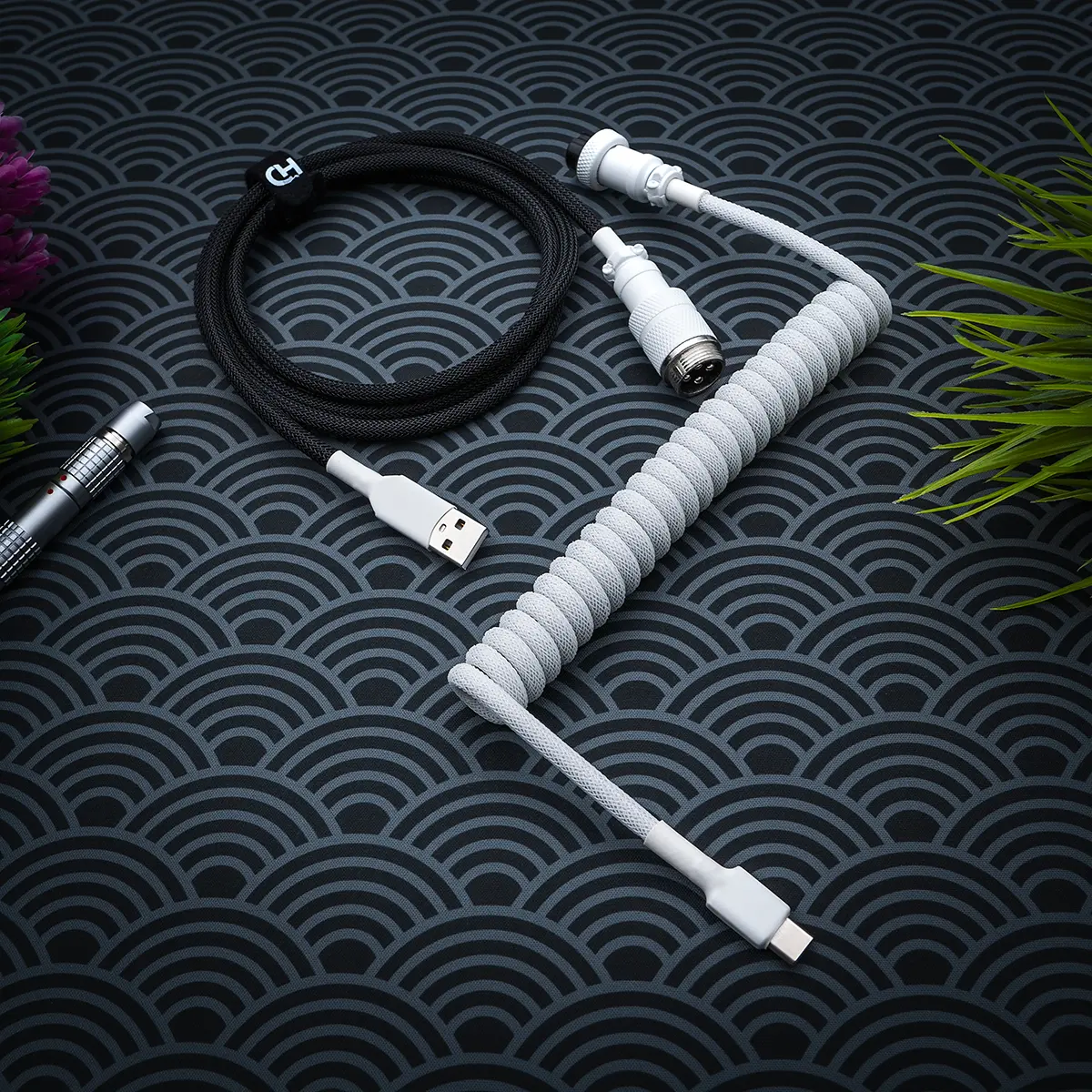 Curled white paracord cable with USB-C and aviator connectors, plus a black straight section, showcasing high-quality braiding and finish.