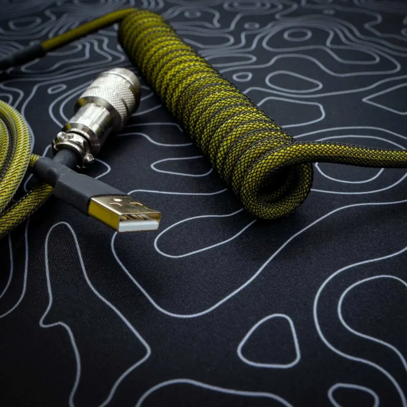 Coiled keyboard cable in yellow and black paracord, featuring a gold-plated USB connector and detachable aviator plug. Durable, vibrant design.