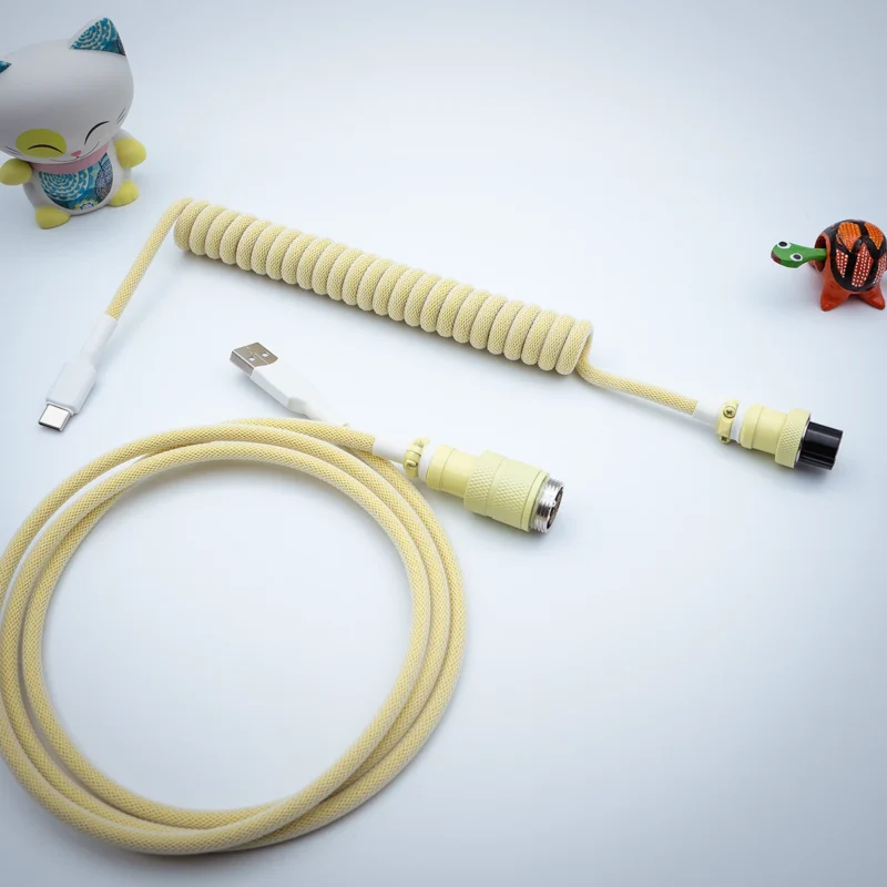 Coiled yellow keyboard cable featuring USB-C and detachable connectors. Includes a straight cord section, durable paracord, and high-quality finishes.